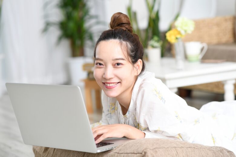 ノートパソコンを使いながら微笑んでいる女性